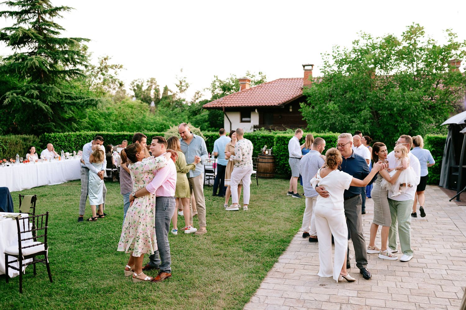 Guests dancing together on an outdoor patio during a summer evening celebration.