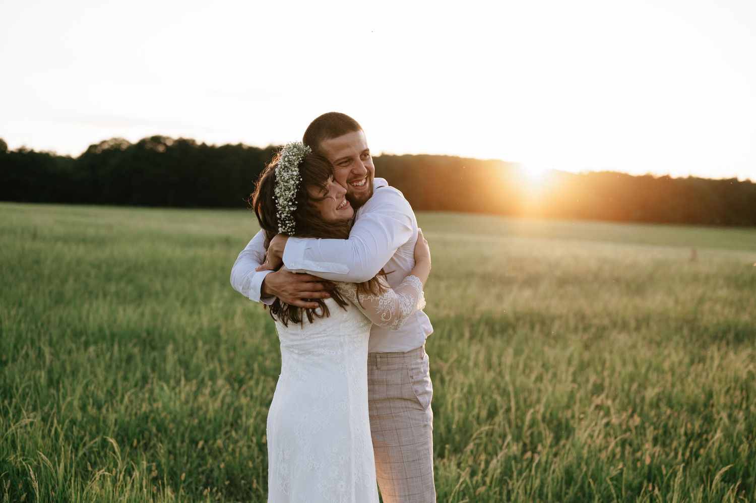 A romantic sunset embrace in a golden wheat field during a wedding photoshoot.
