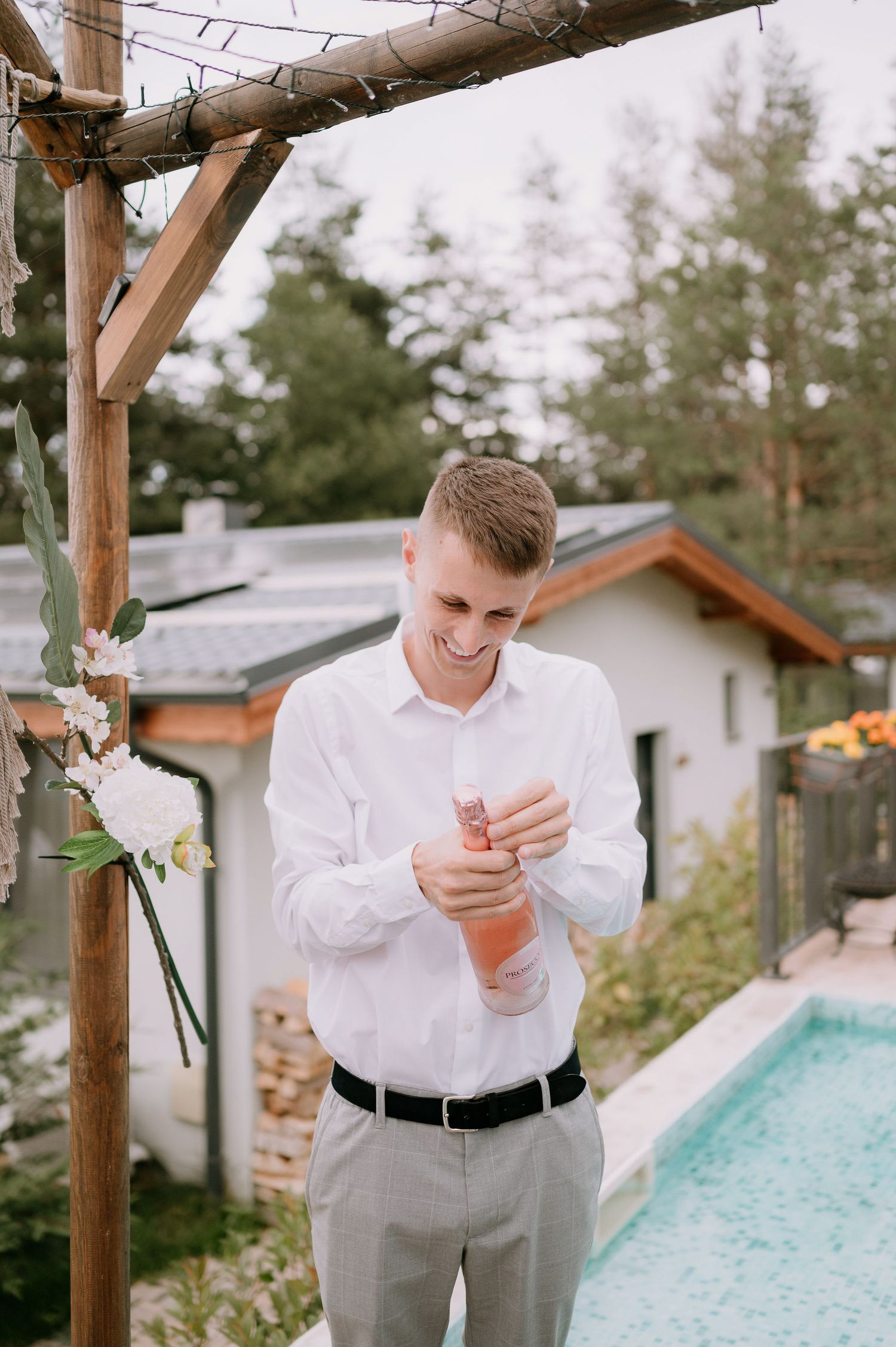 Person in formal white attire examining something in their hands near a pool area.