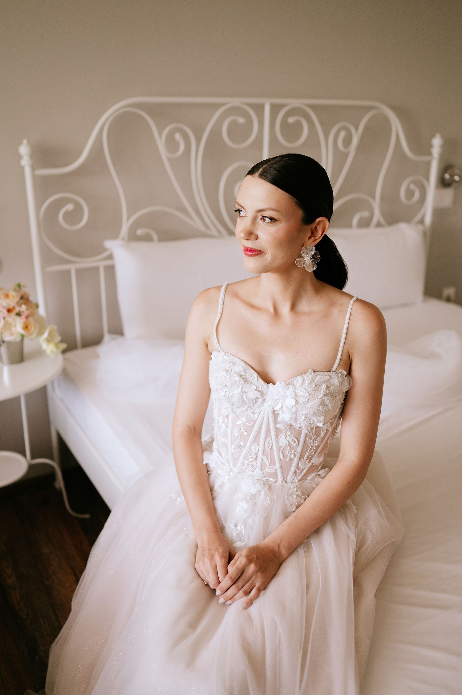 Wedding dress with detailed lace bodice and flowing tulle skirt photographed in bedroom setting.