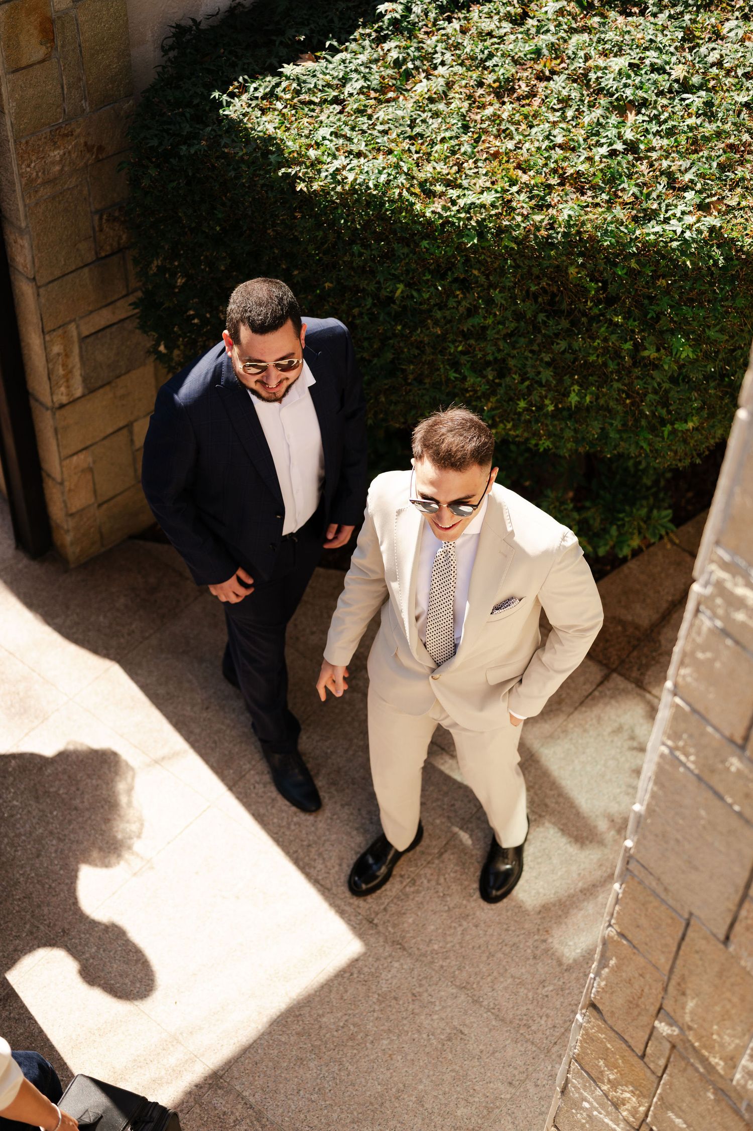High angle view of people in formal attire standing on stone steps in dappled sunlight.