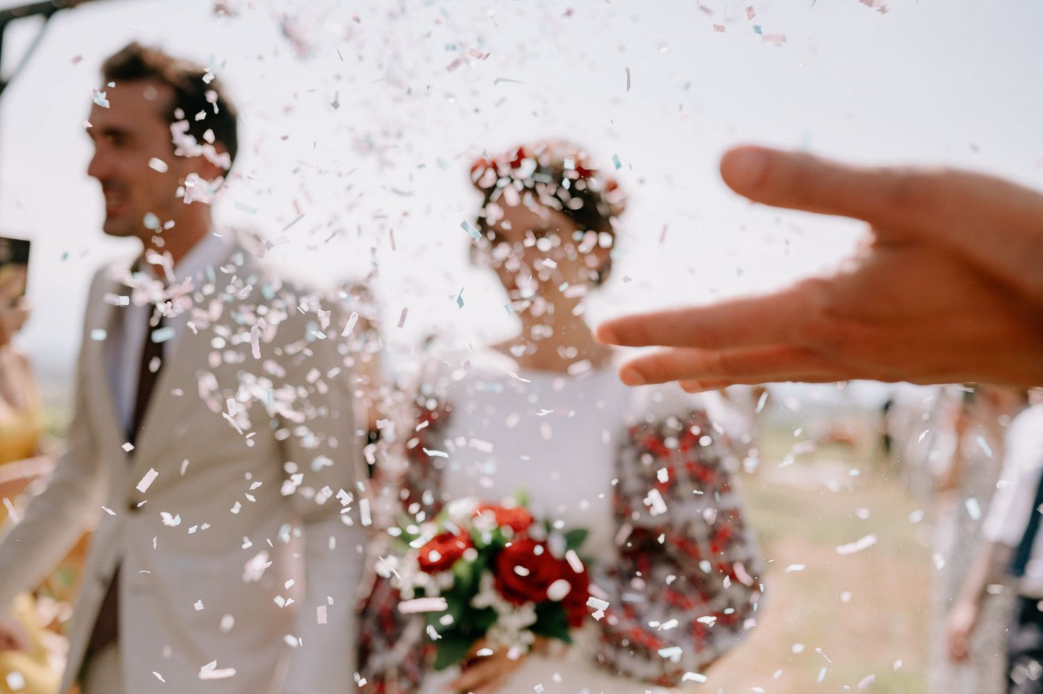 Confetti fills the air during a joyous outdoor wedding celebration.