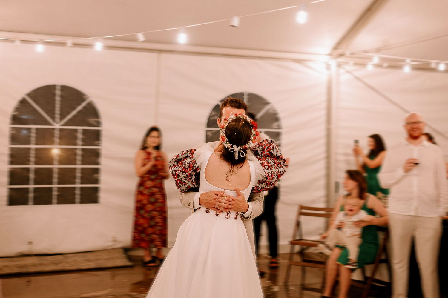 Guests dancing and celebrating at a lively wedding reception under string lights.