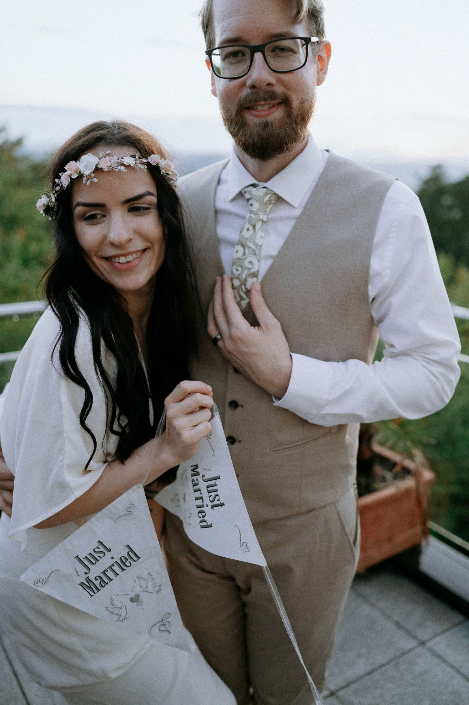 Couple shares joyful moment with 'Just Married' banners on outdoor terrace.