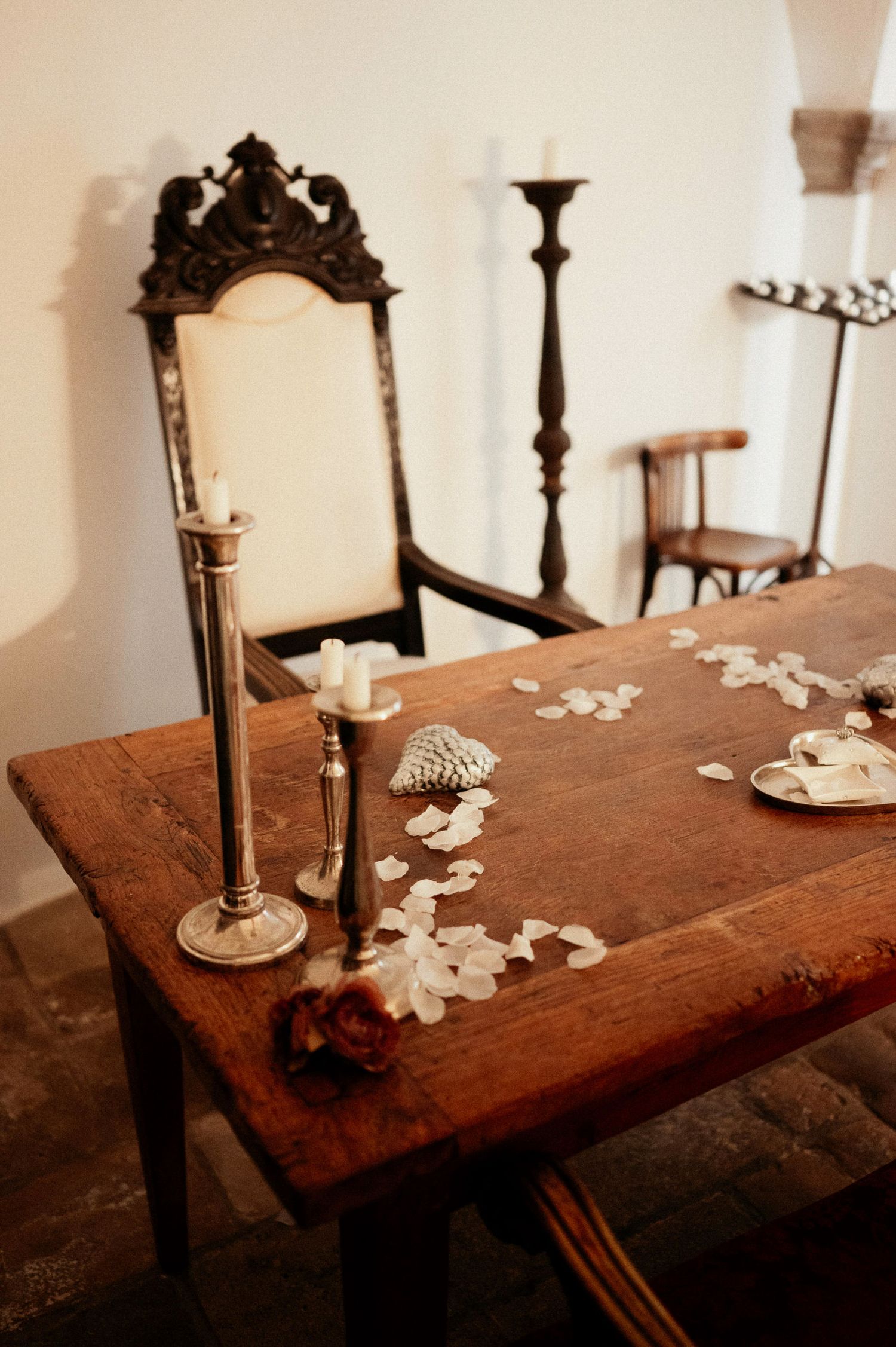Vintage wooden table decorated with candlesticks and scattered rose petals.