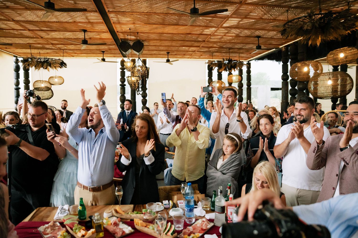 Wedding celebration with guests cheering in a rustic venue with wooden ceiling details.