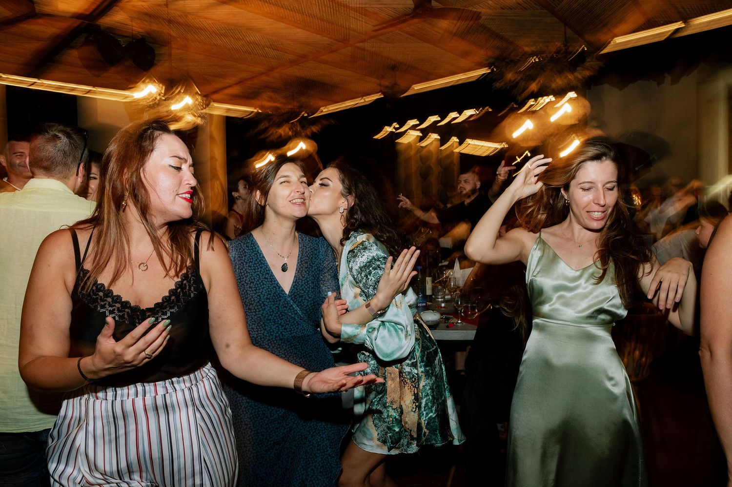 People dancing and socializing at a festive indoor celebration with warm lighting.