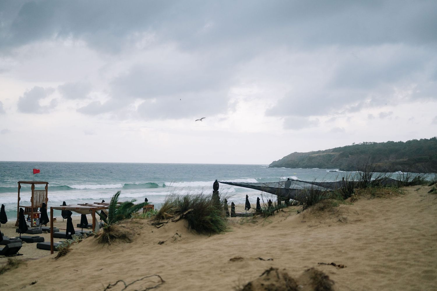 Panoramic view of a cloudy coastline with wooden boardwalk and beach dunes.