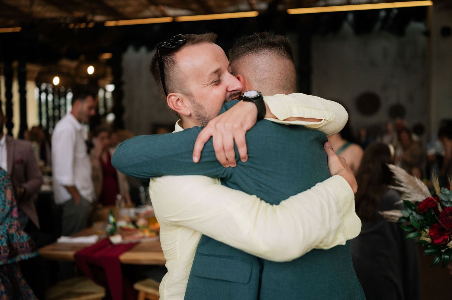 Emotional wedding moments captured in a dimly lit reception space with warm ambiance.