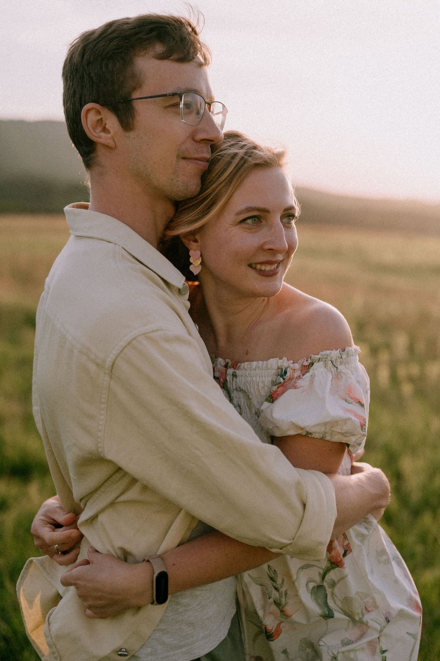 A tender embrace captured in warm evening light amidst a wildflower meadow.