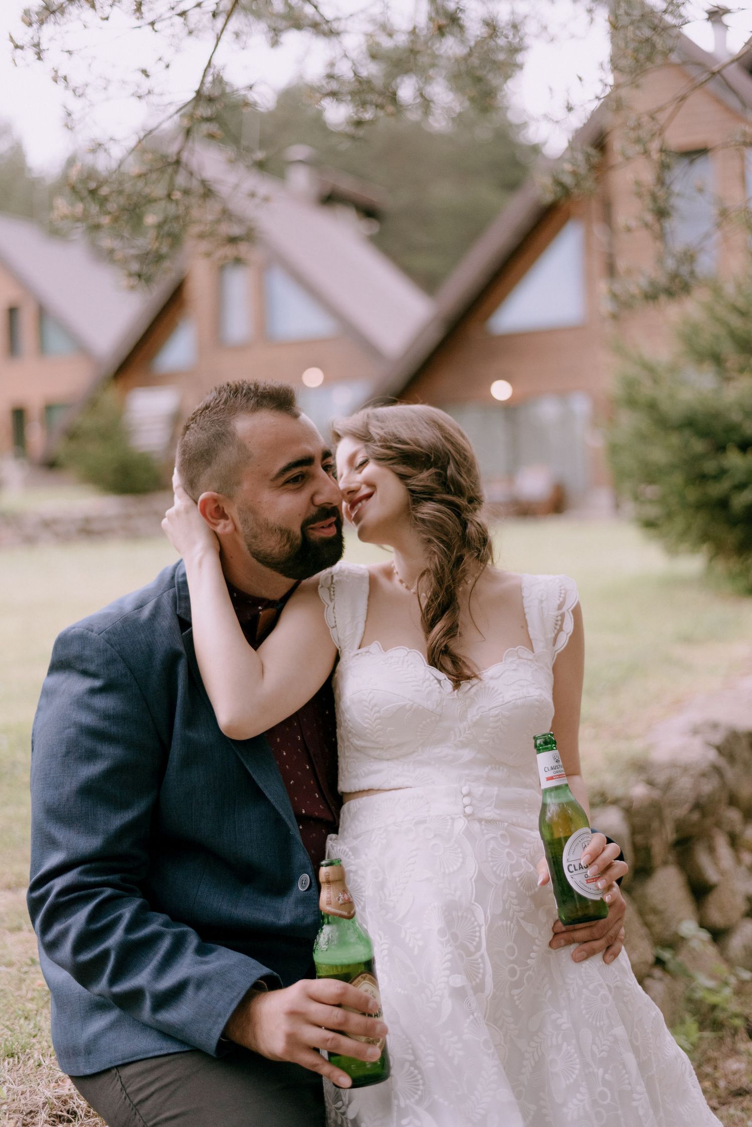 A couple shares playful moments with beverages against a rustic cabin backdrop.
