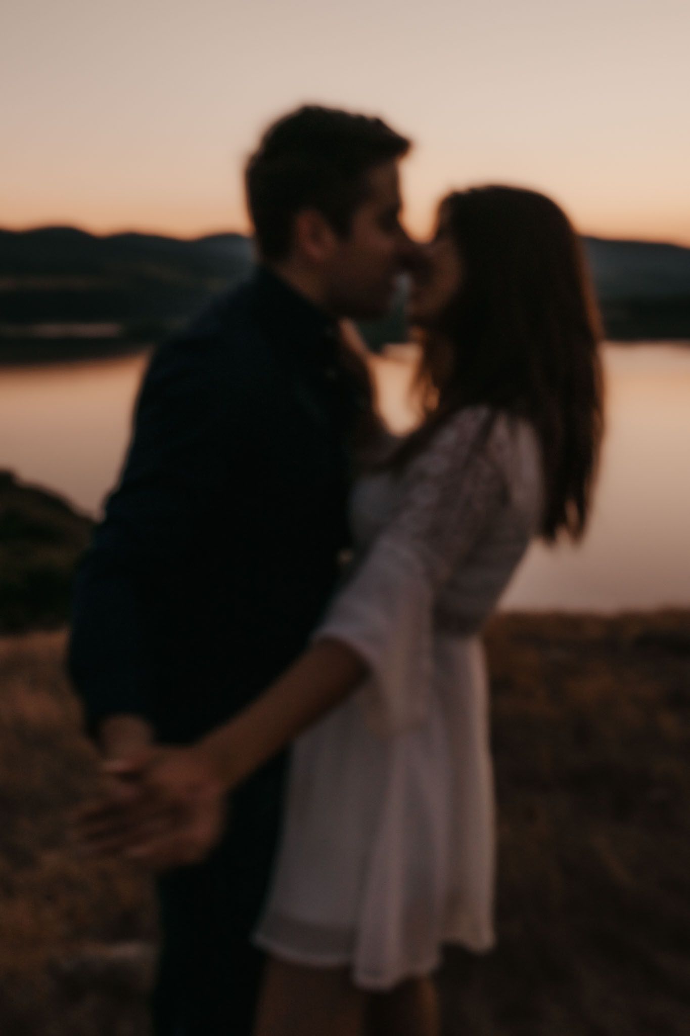 Romantic silhouettes against sunset lake backdrop.
