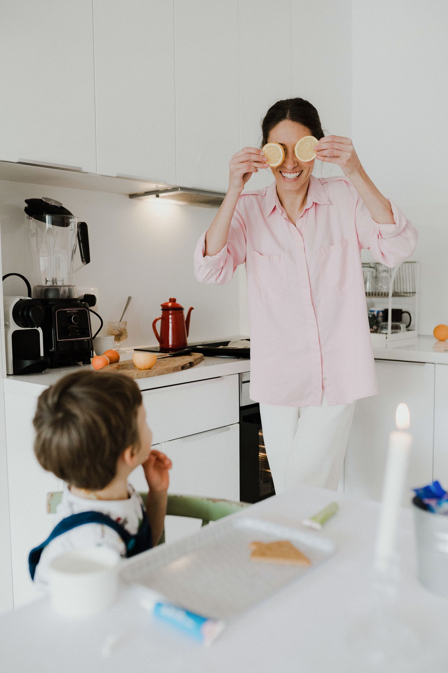 A series of photos showing someone in a pink shirt moving through a bright white kitchen with modern appliances.