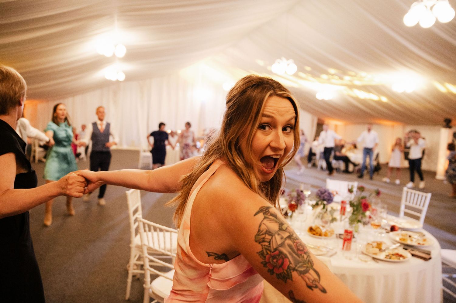 A sequence of candid moments from a wedding reception shows dancing and celebration in a white tent venue.