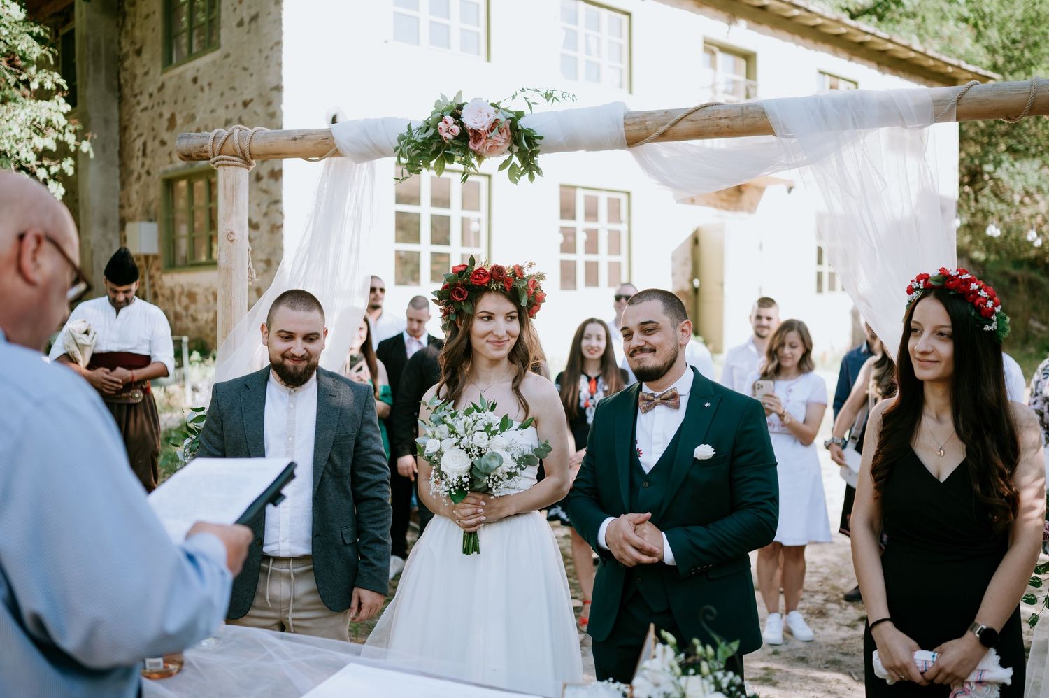 Wedding ceremony setup with white backdrop against stone building exterior.