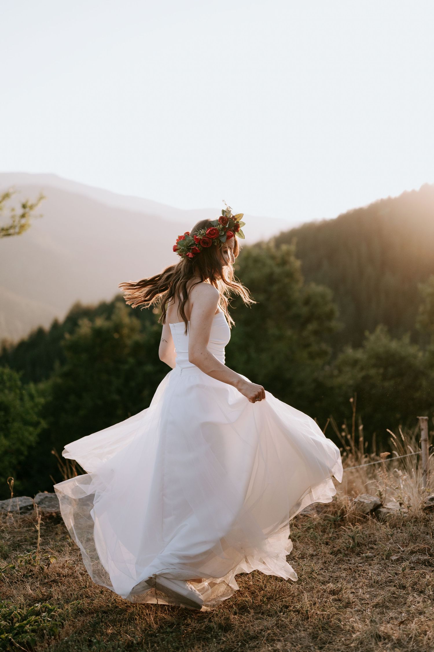 Elegant white gown flows dramatically during a sunset mountain photography session.