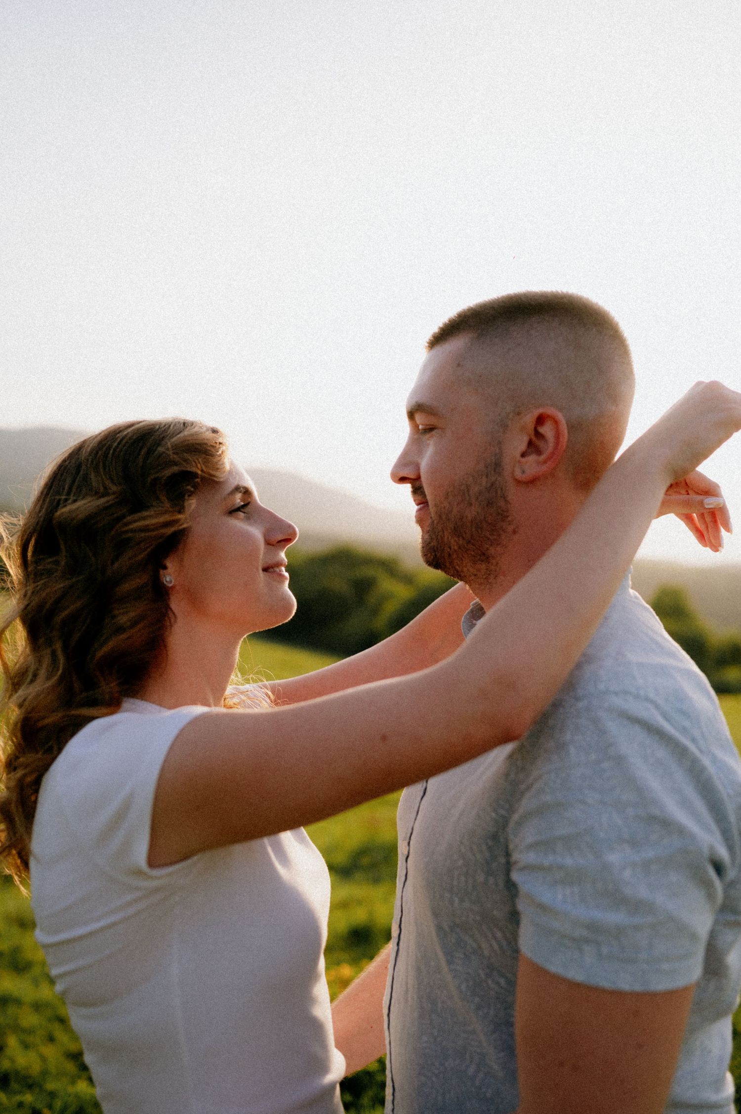 Couple performing romantic dance moves against a backdrop of rolling hills at sunset.