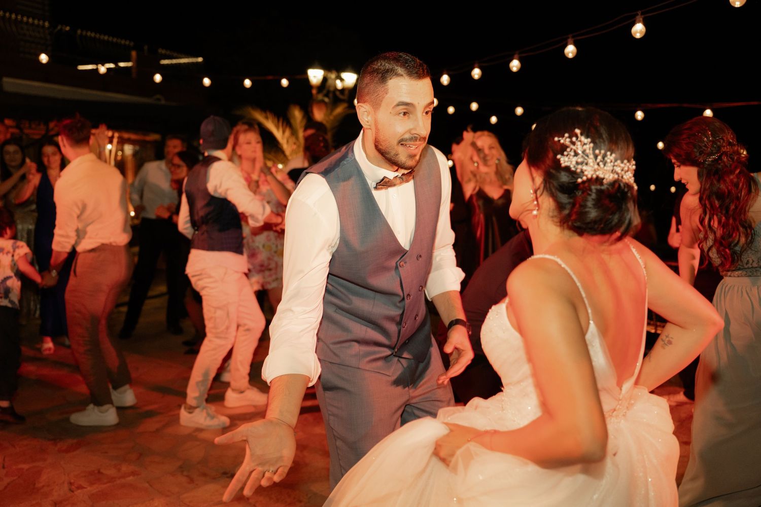 Couples dance together at a lively evening reception with warm lighting and festive atmosphere.