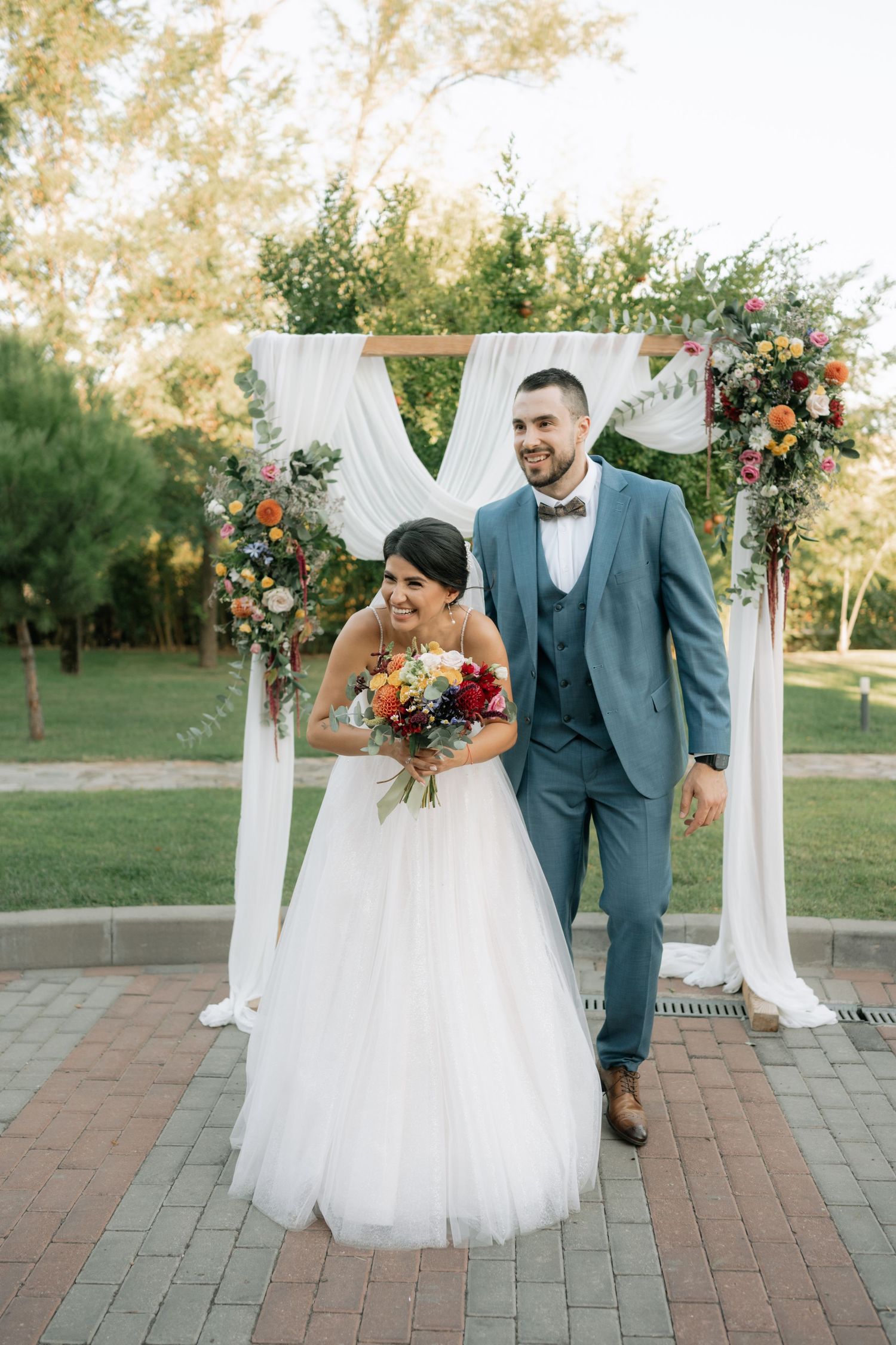 Outdoor wedding ceremony setup with floral arch and brick pathway capturing romantic moments during sunset.