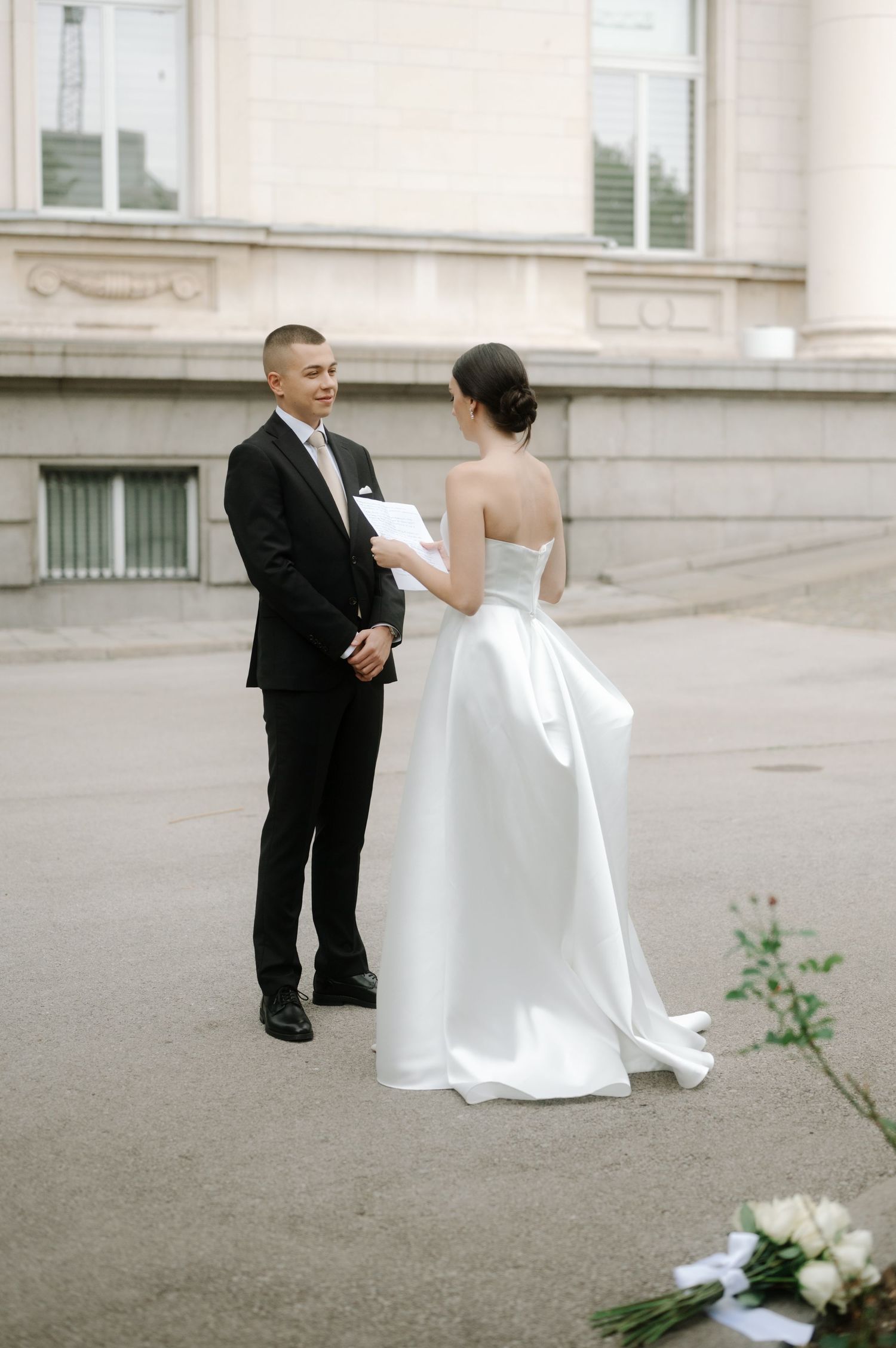 A couple in wedding attire shares a tender moment on stone steps during their outdoor photo session.