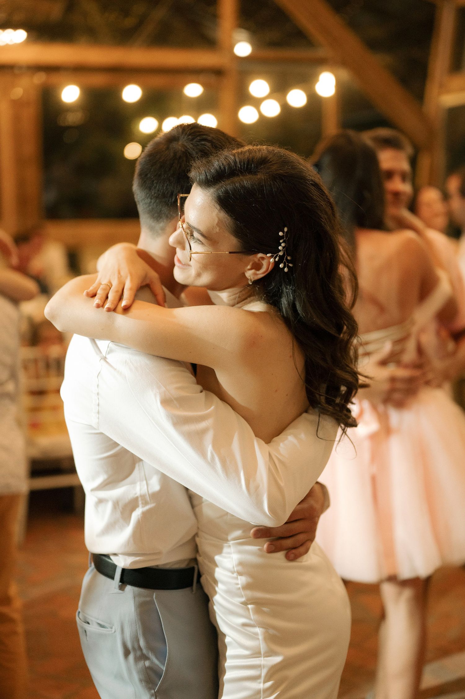 A series of romantic dance poses between a couple in wedding attire, with string lights glowing in the background.