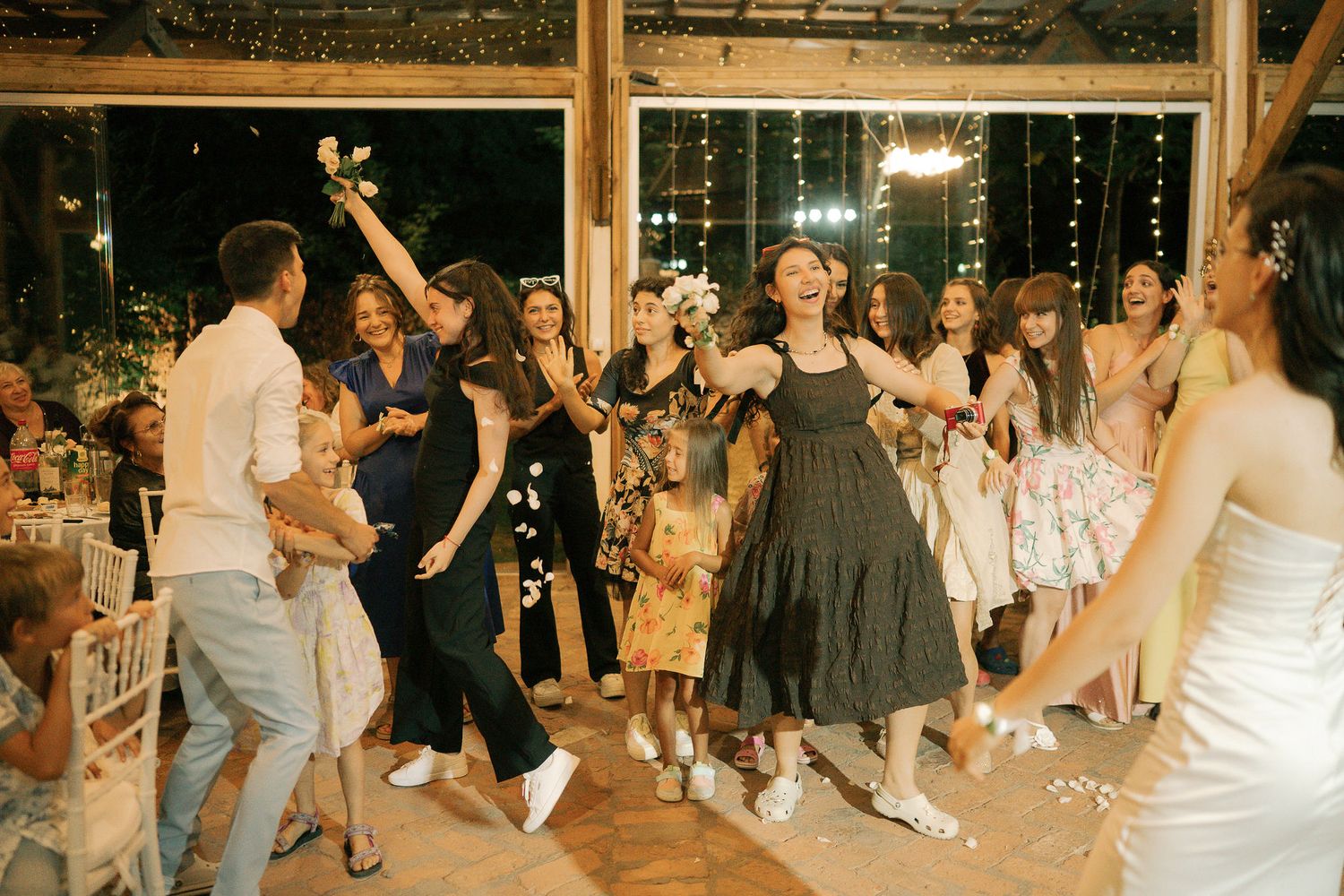 Wedding guests dance and celebrate on a wooden dance floor during an evening reception.