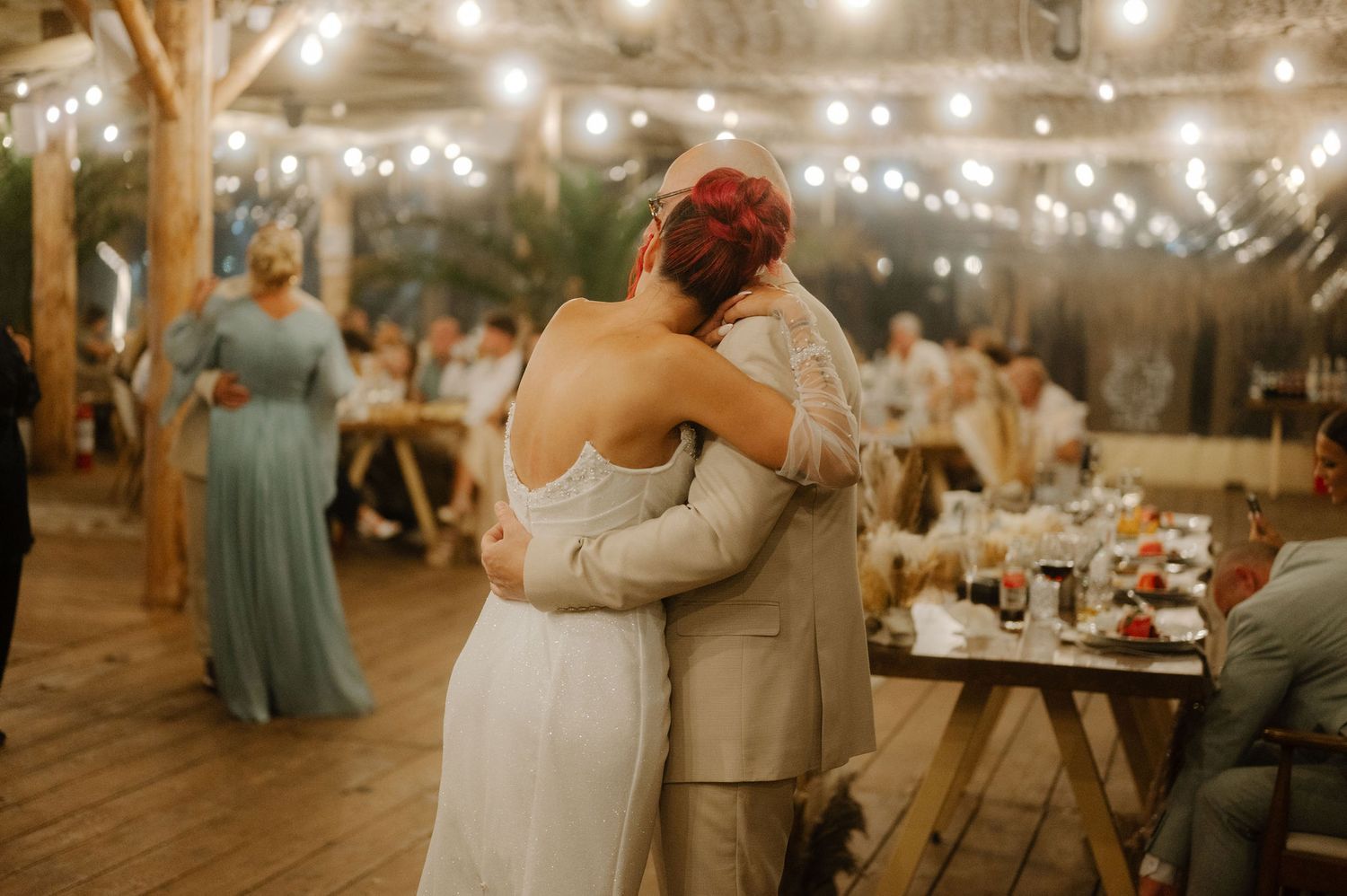A romantic first dance sequence at a wedding reception under twinkling string lights and rustic decor.