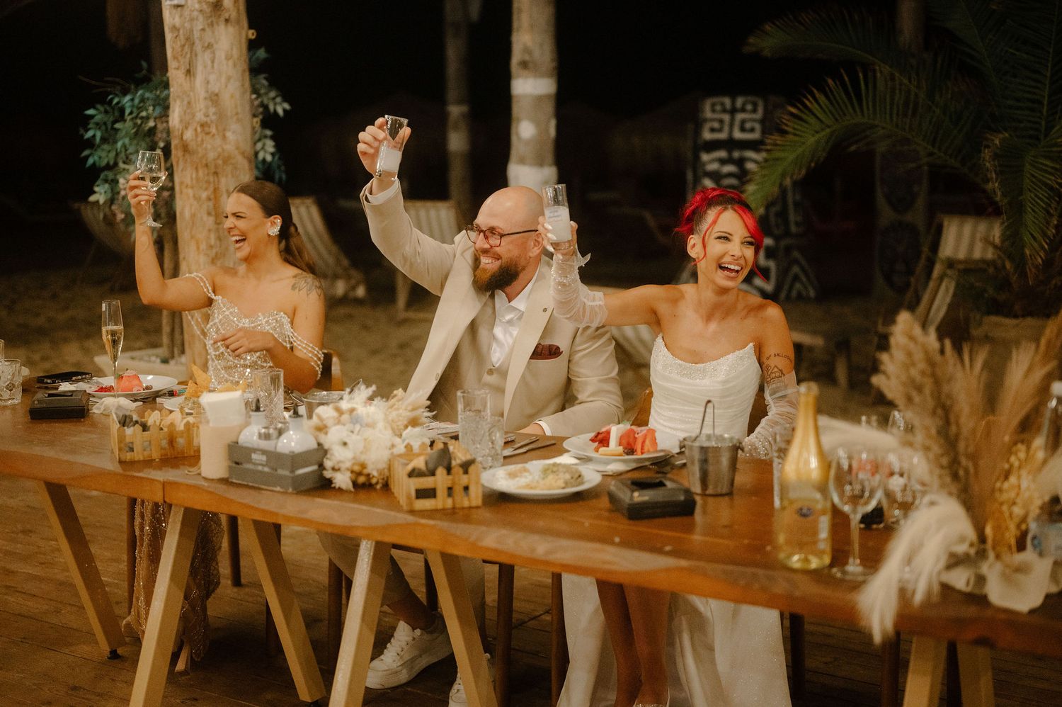 Rustic outdoor wedding reception table setting with white floral arrangements and vintage decor at sunset.