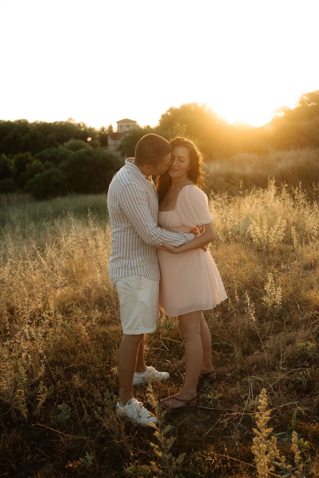 A couple embraces in a golden field at sunset creating a romantic silhouette against the warm glowing sky.
