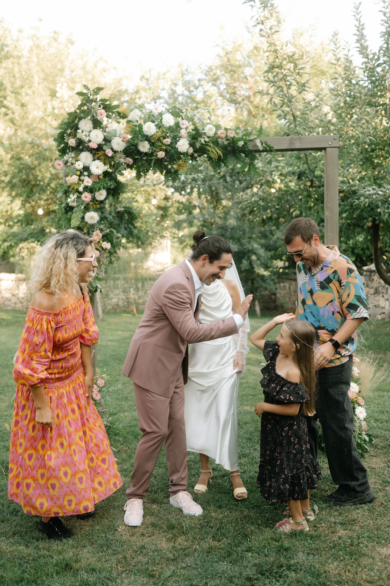 A playful sequence of wedding party photos shows couples dancing and posing together in a garden setting.