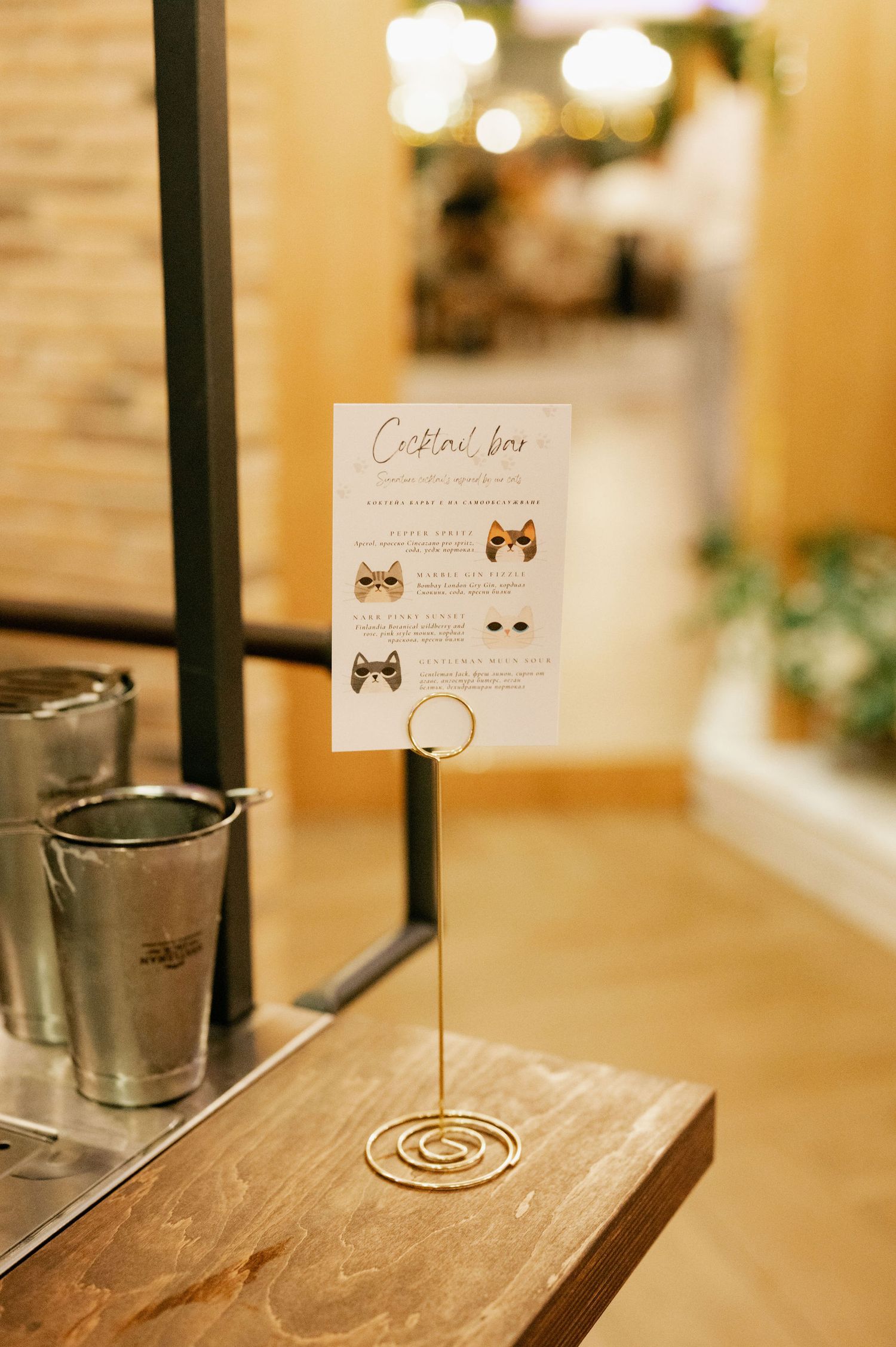 A rustic wooden table displays custom table cards and silver candle holders in warm lighting at a wedding reception.