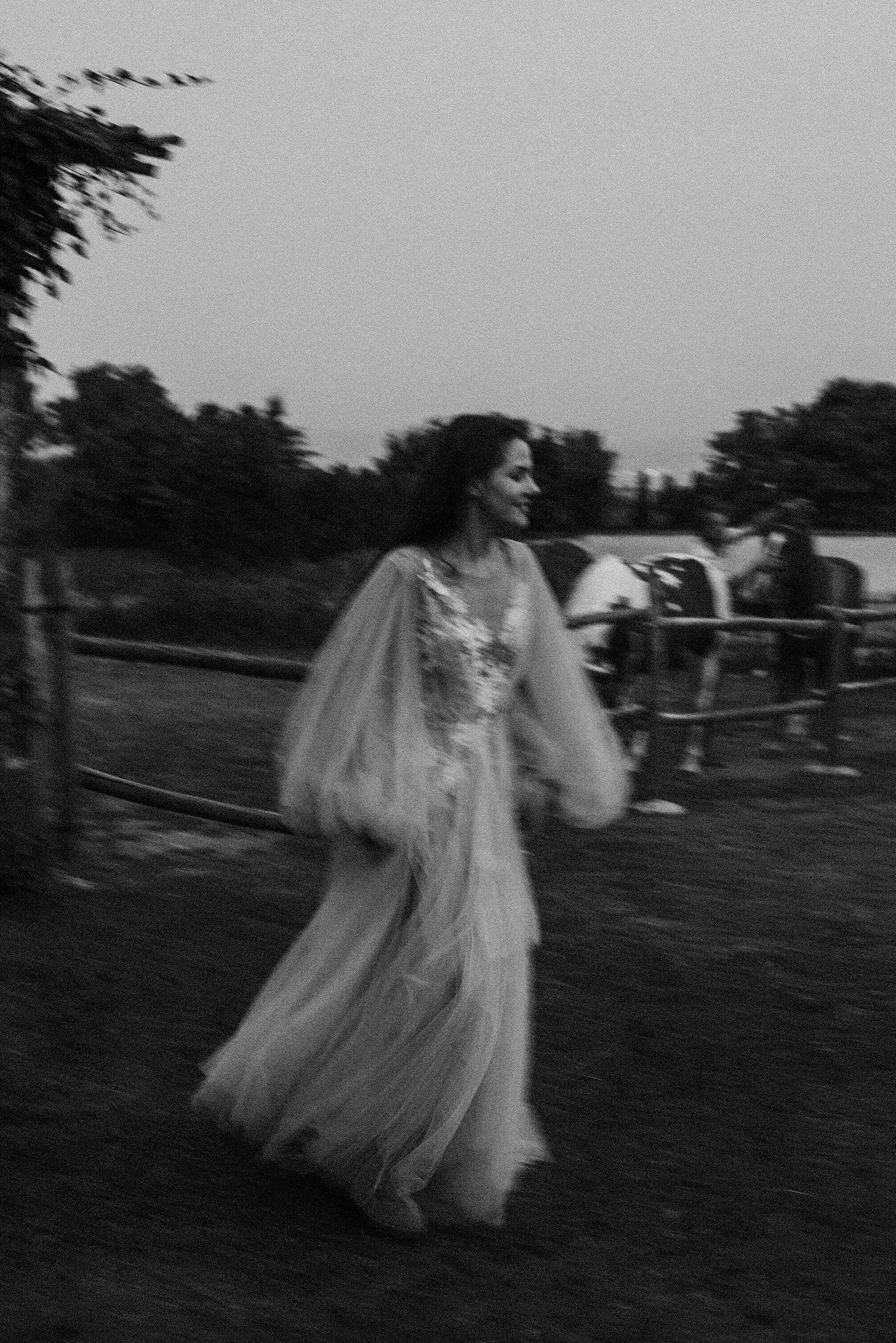 A series of blurry black and white photos showing ethereal figures in flowing white dresses moving through a dark field.