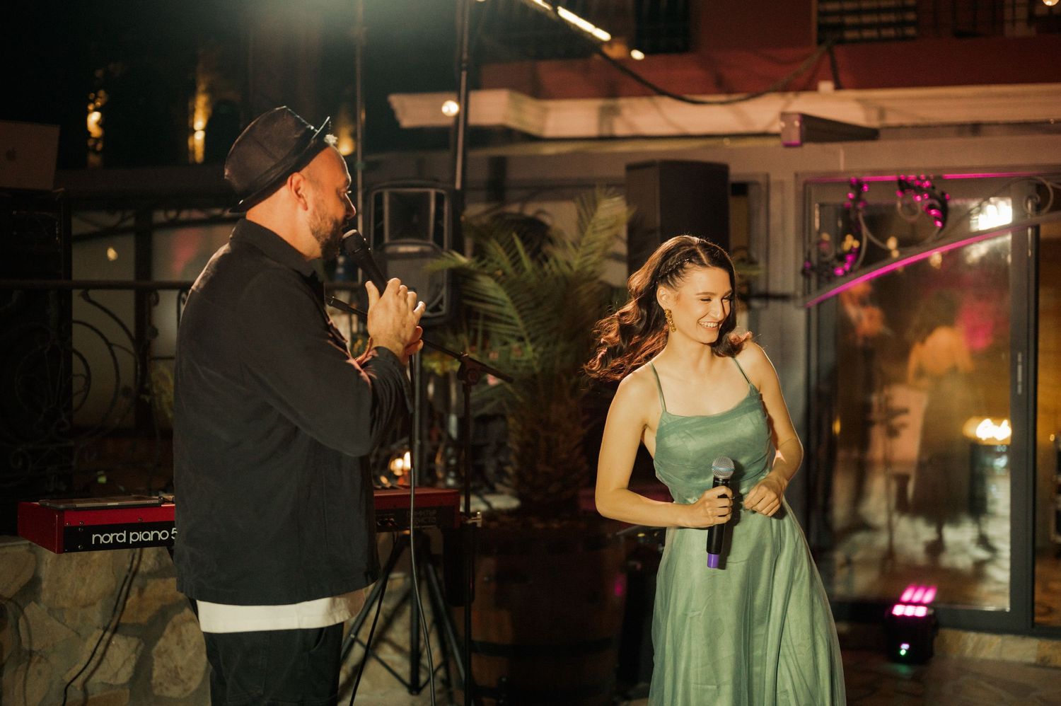 A couple dances together in an intimate moment during a dimly lit indoor event.