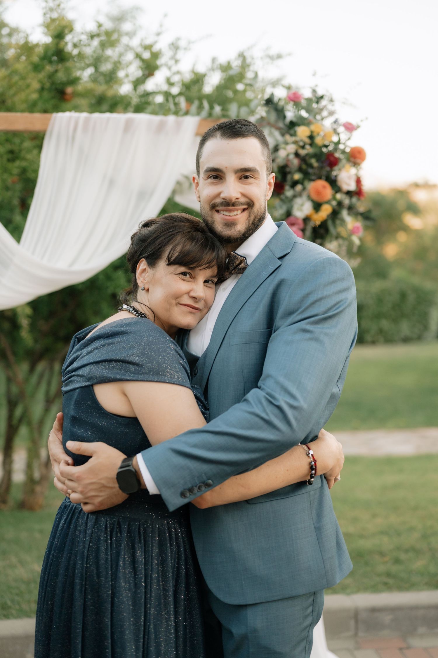 A couple embraces outdoors in formal attire during a romantic photo session at sunset.
