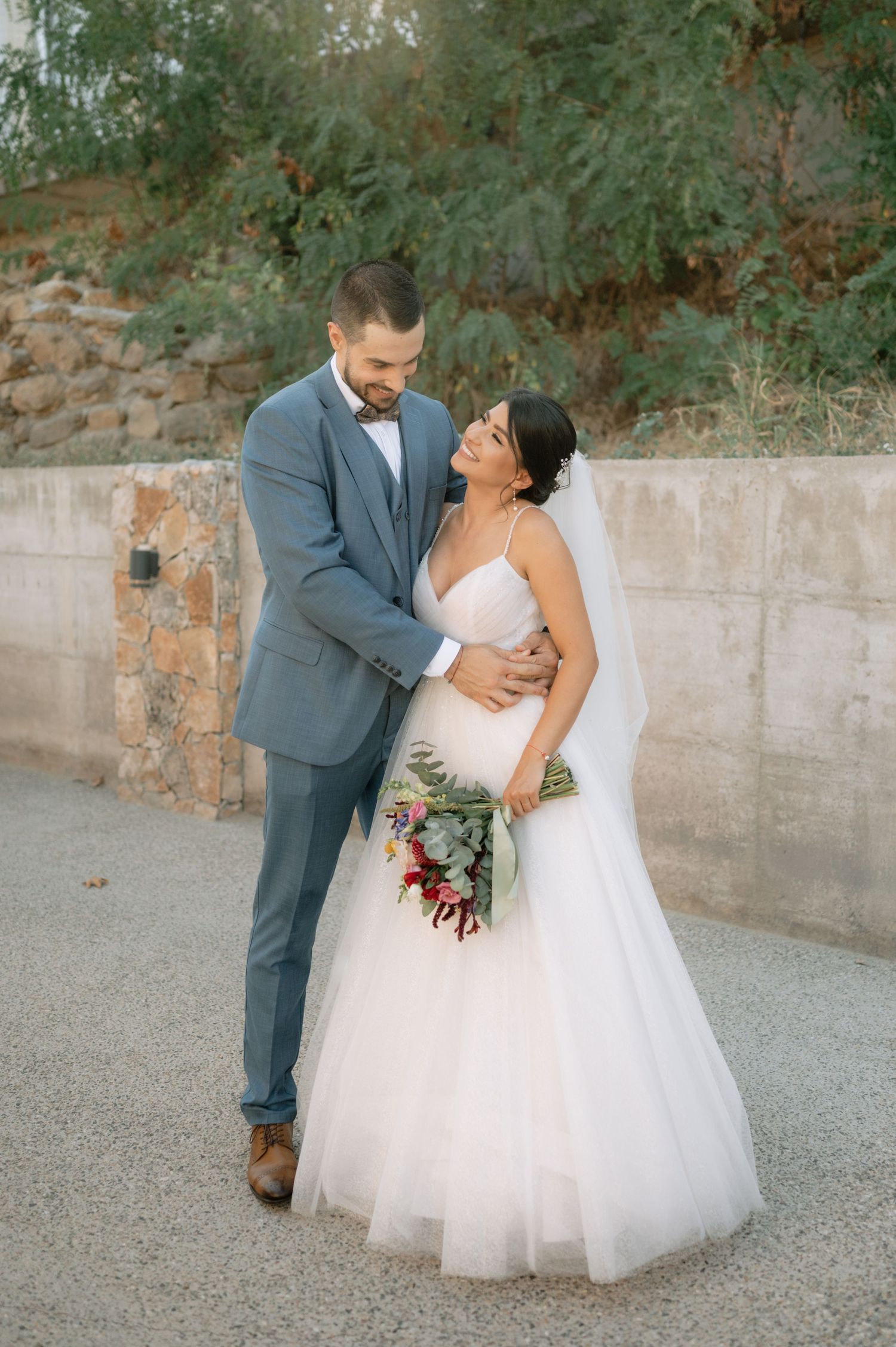A romantic wedding moment captured in a series of photos showing a couple in formal attire against a stone wall backdrop.