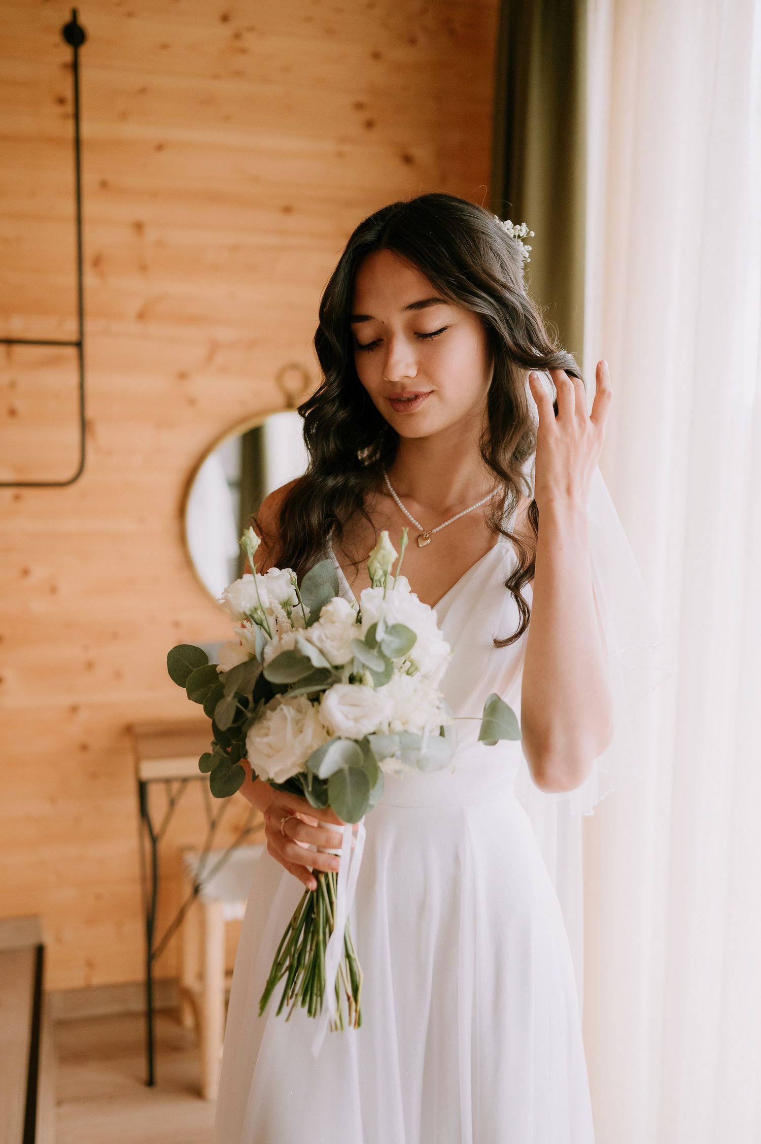 Soft natural light bridal photos with white floral bouquet against wooden walls.