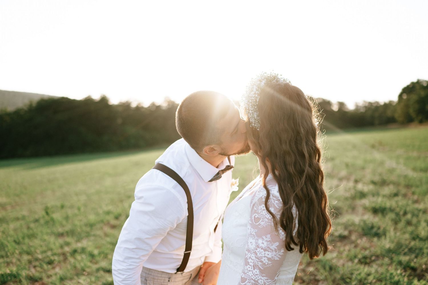 Couple shares intimate moment in golden sunlight during outdoor wedding photoshoot.