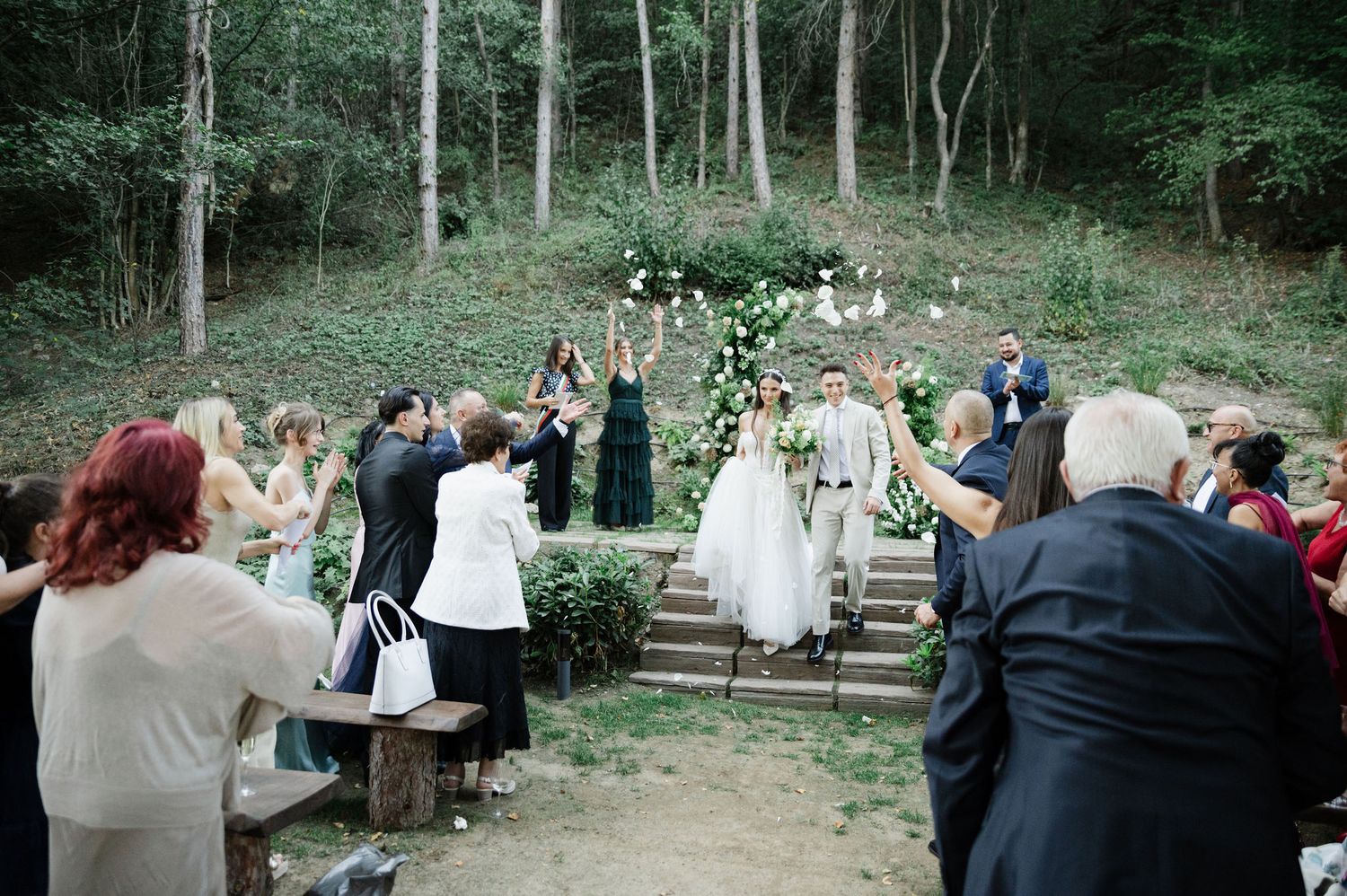 Wedding celebration in a rustic woodland setting with stone steps and natural decor.