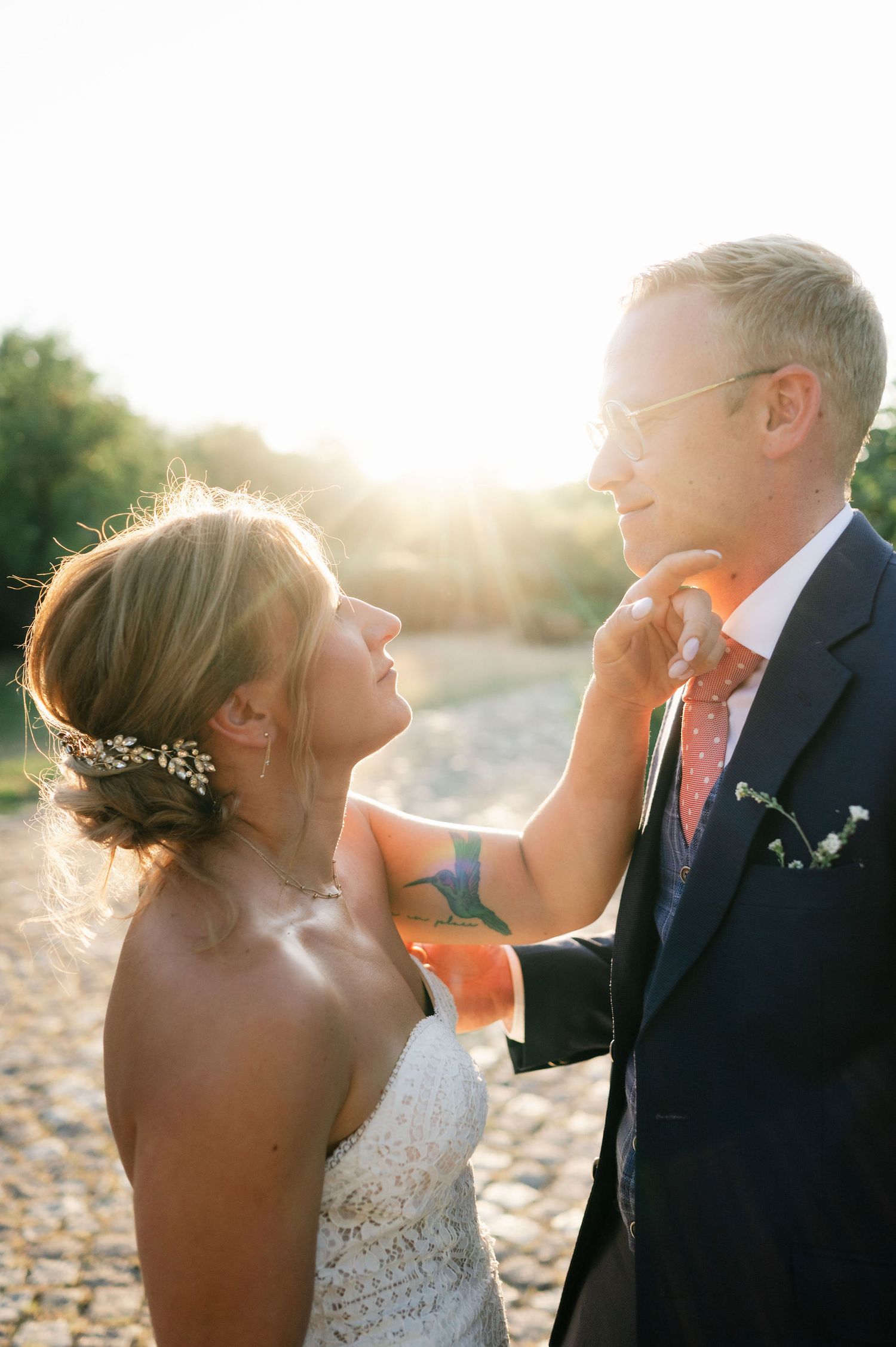 Newlyweds embrace during sunset photoshoot with soft glowing backlight.