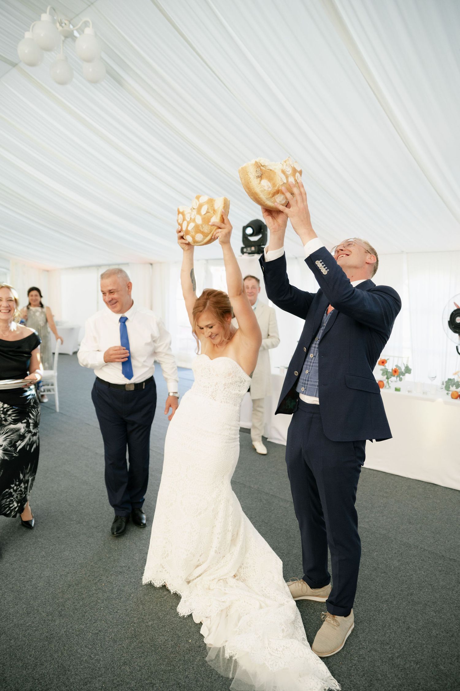 Wedding couples dancing and twirling in a white tent on dark carpet.