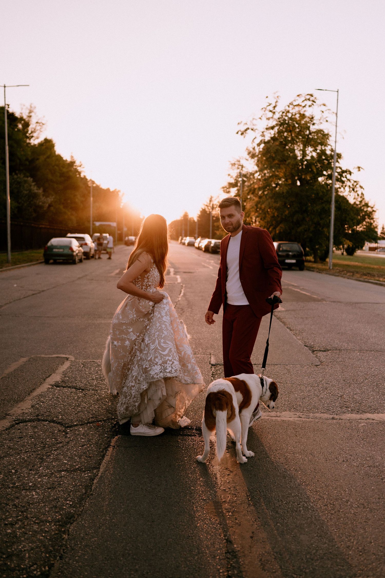 Couple and their dogs share a moment together on a street during sunset.