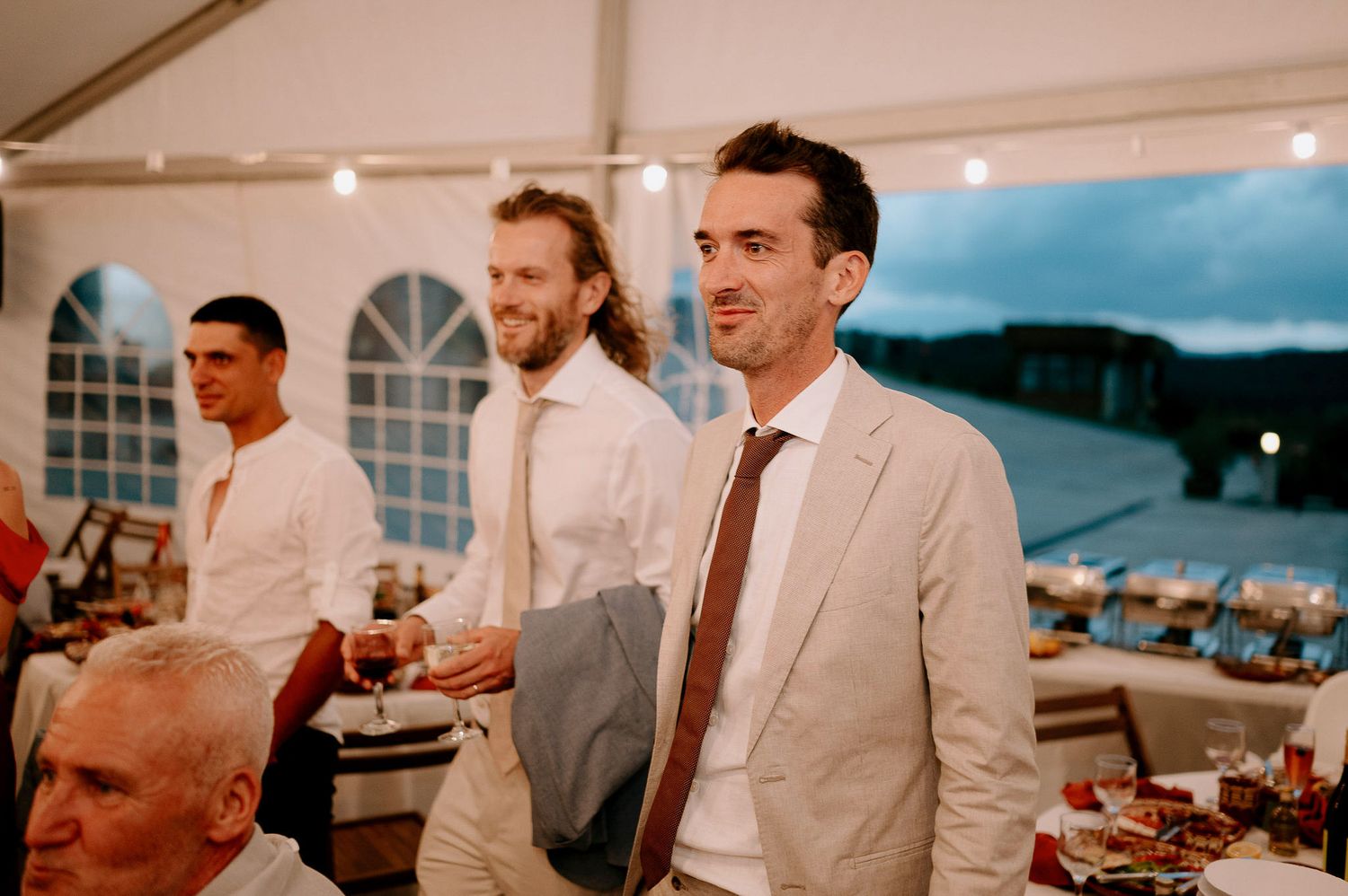 Wedding reception venue with white decor and scenic water view visible through windows.