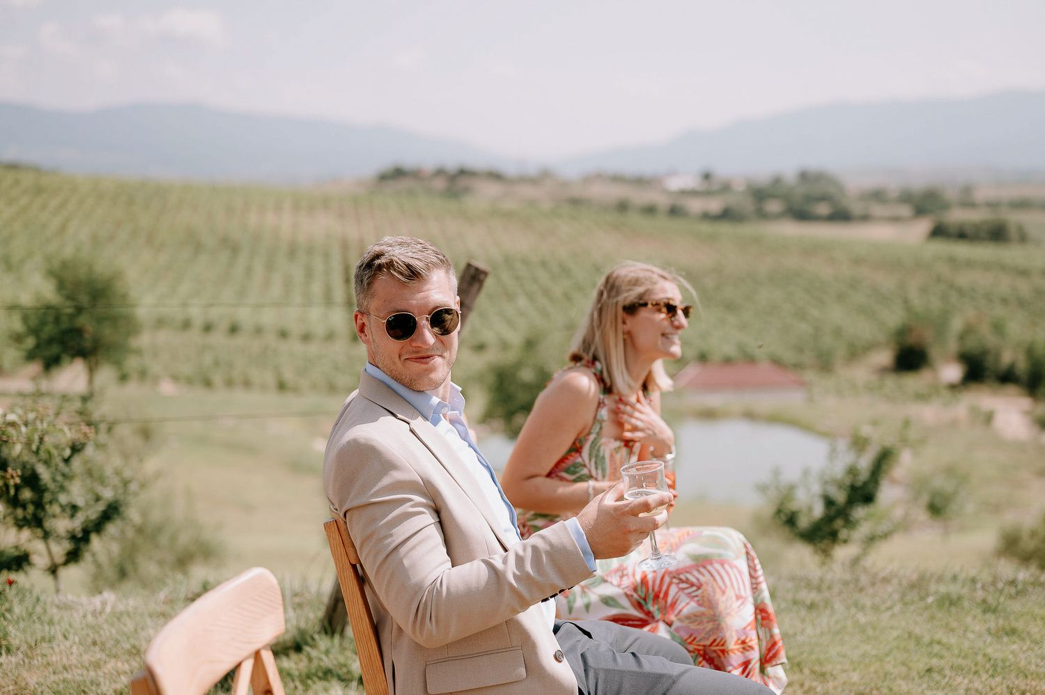 Wedding guests enjoying drinks outdoors with scenic mountain views in the background.