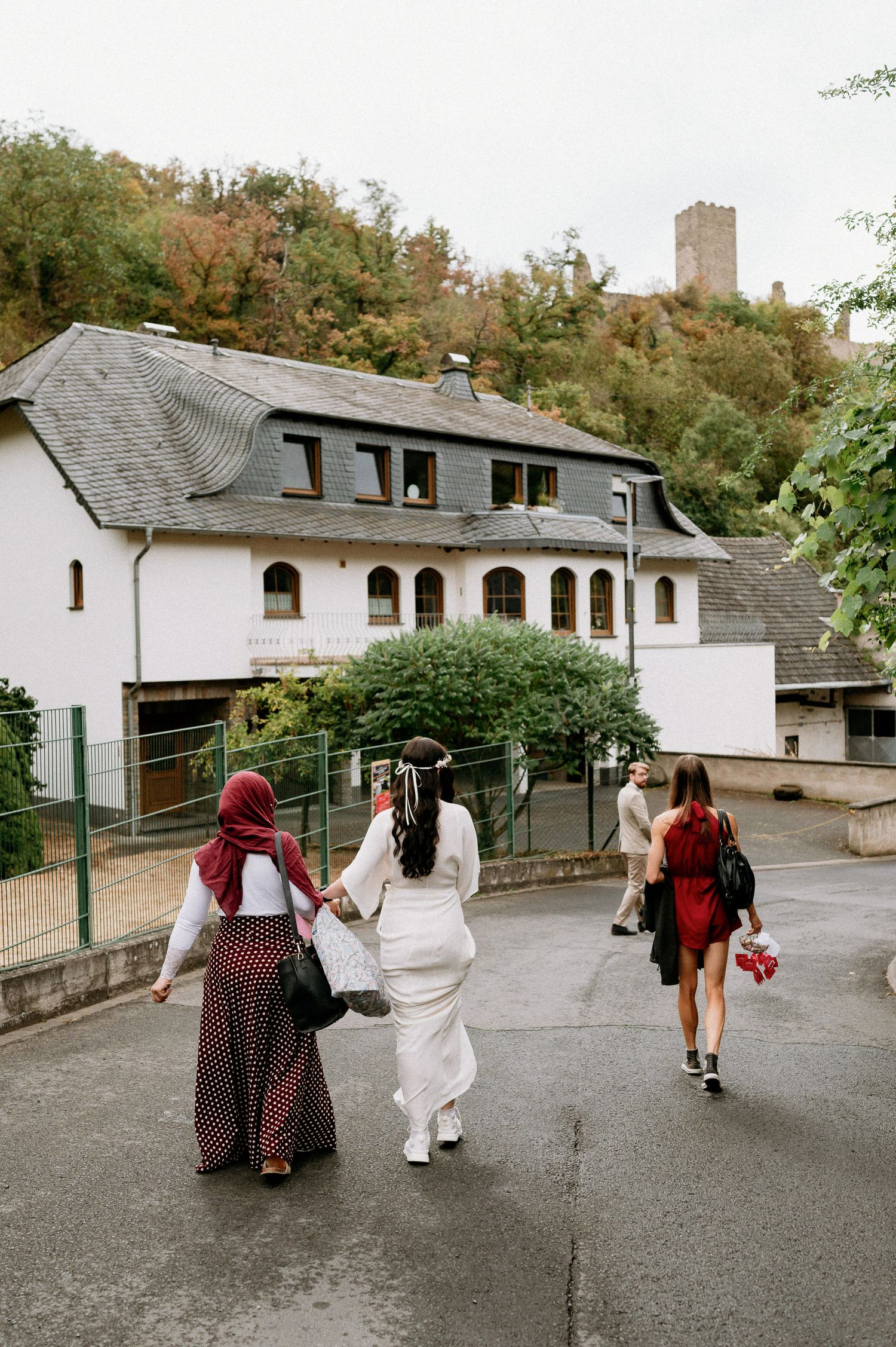 Group walking down a residential street towards white buildings with a castle tower visible in the distance.