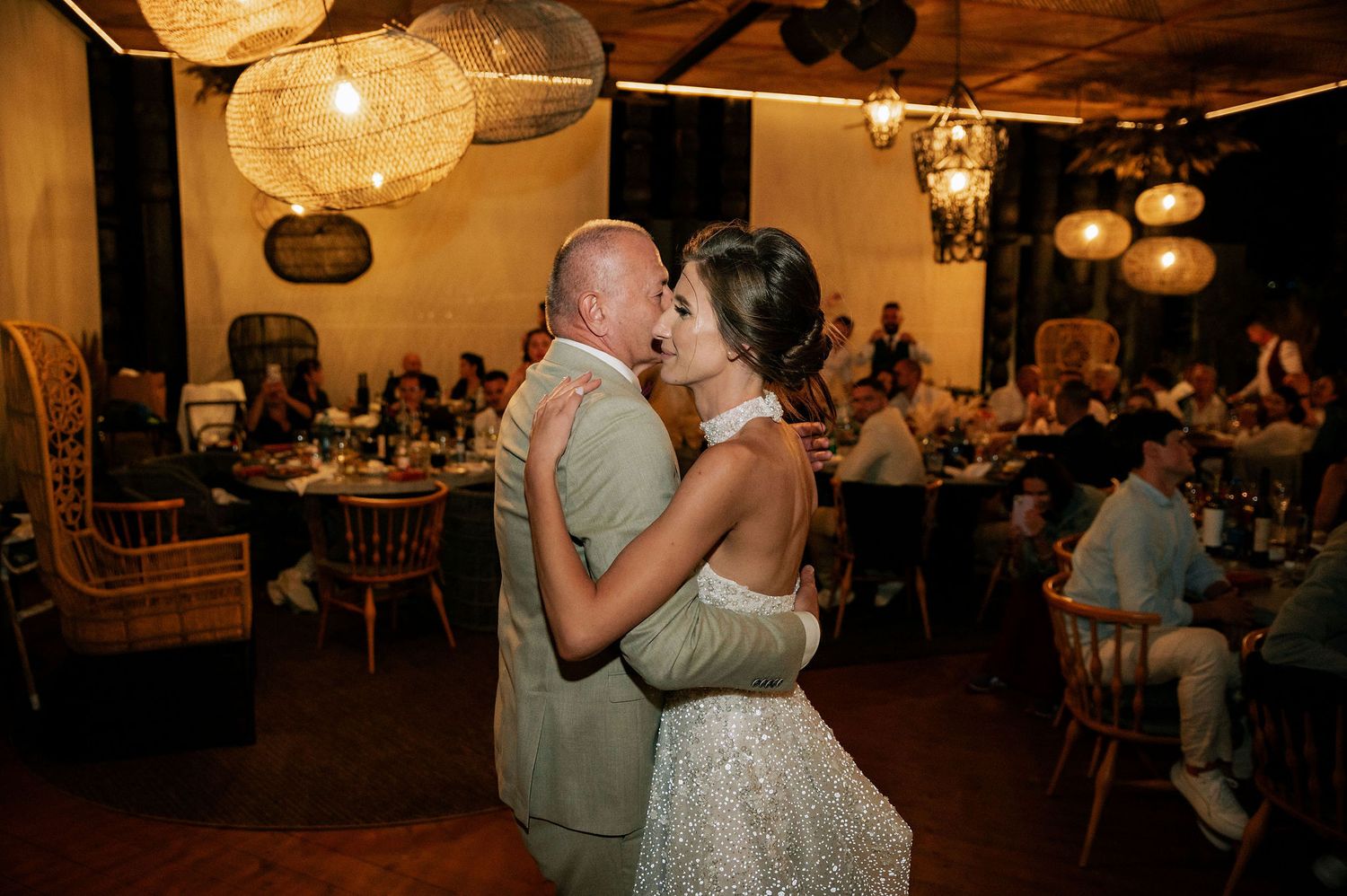 Couples slow dancing at dimly lit wedding reception with hanging lanterns.
