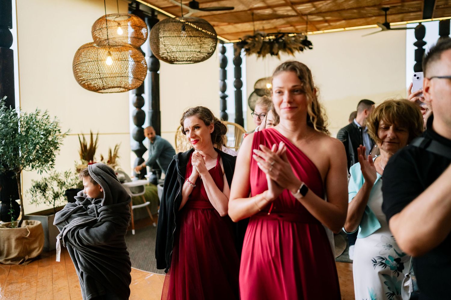 Wedding guests watch emotional ceremony under paper lanterns and wooden beams.