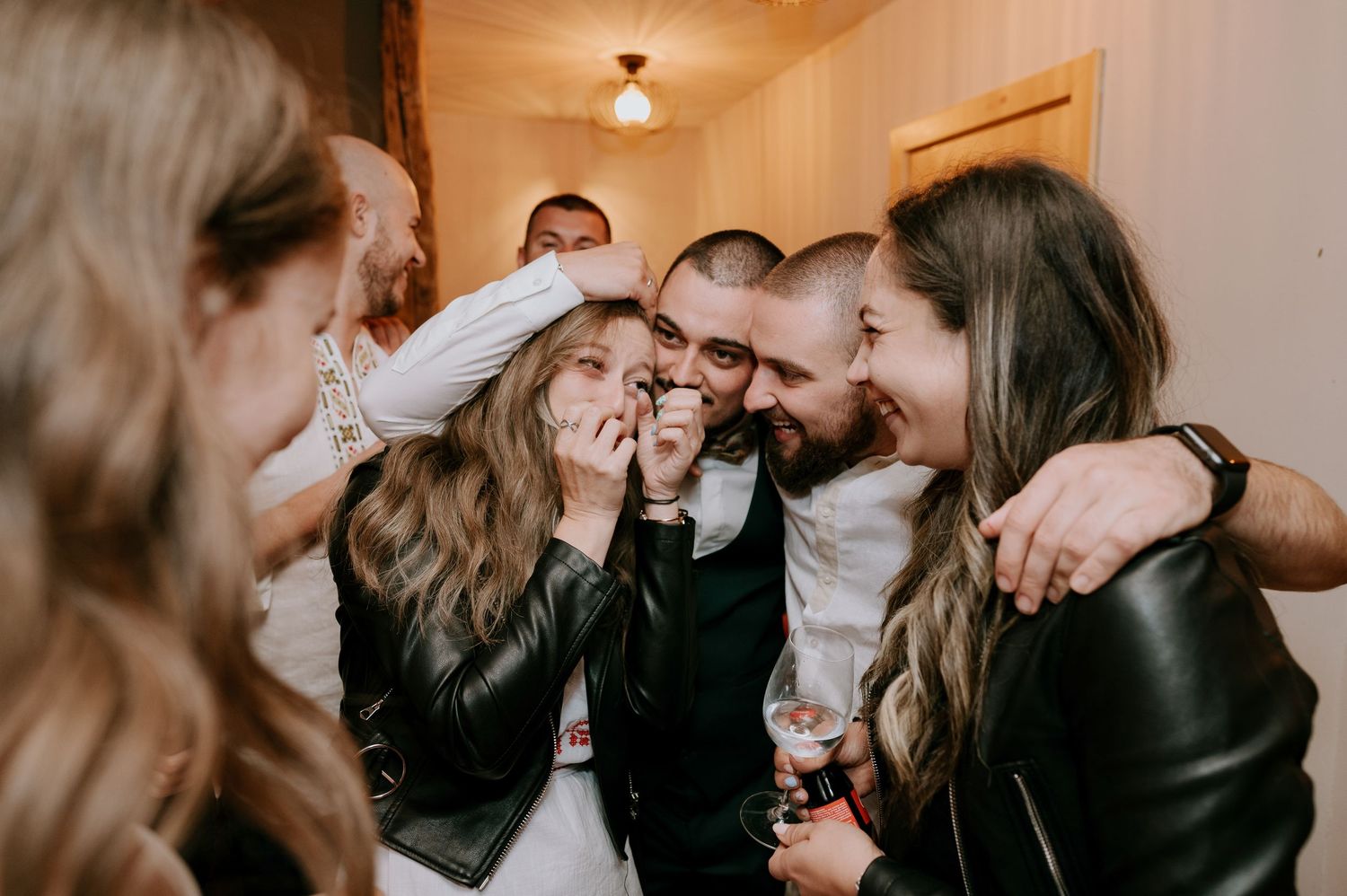 Friends sharing laughter and hugs during an indoor celebration.