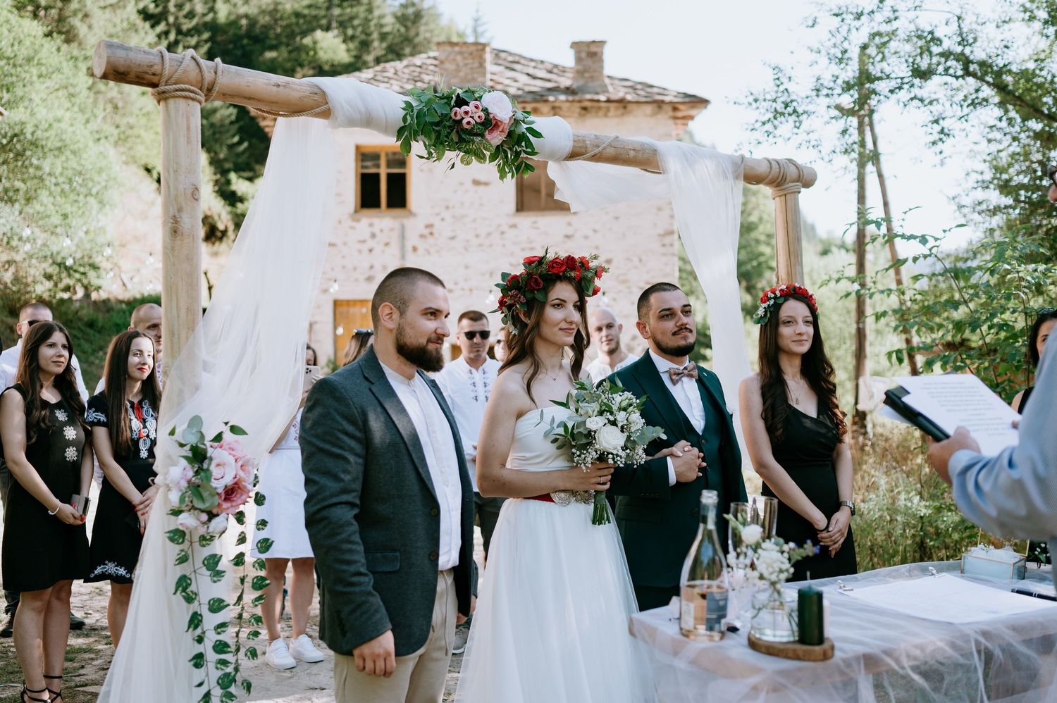 Rustic outdoor wedding reception with elegant white decorations and natural greenery.