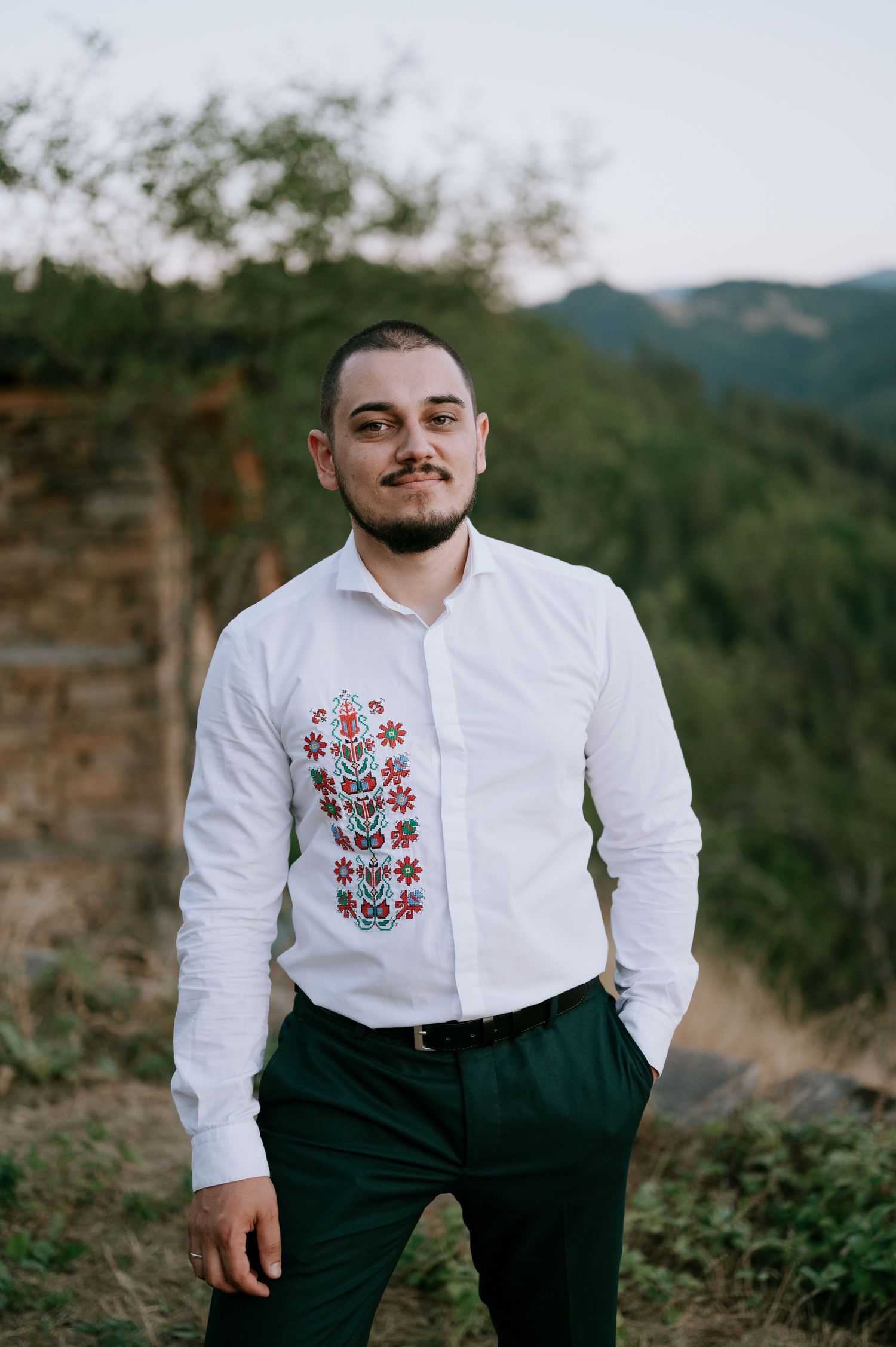 Traditional embroidered white shirt paired with dark pants in an outdoor setting.
