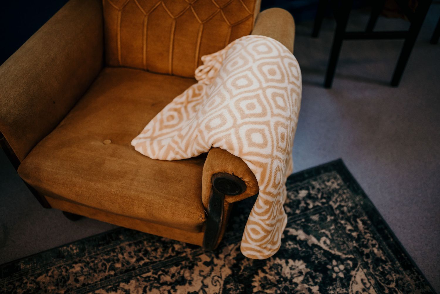 Brown leather armchair with geometric patterned pillow on patterned rug.